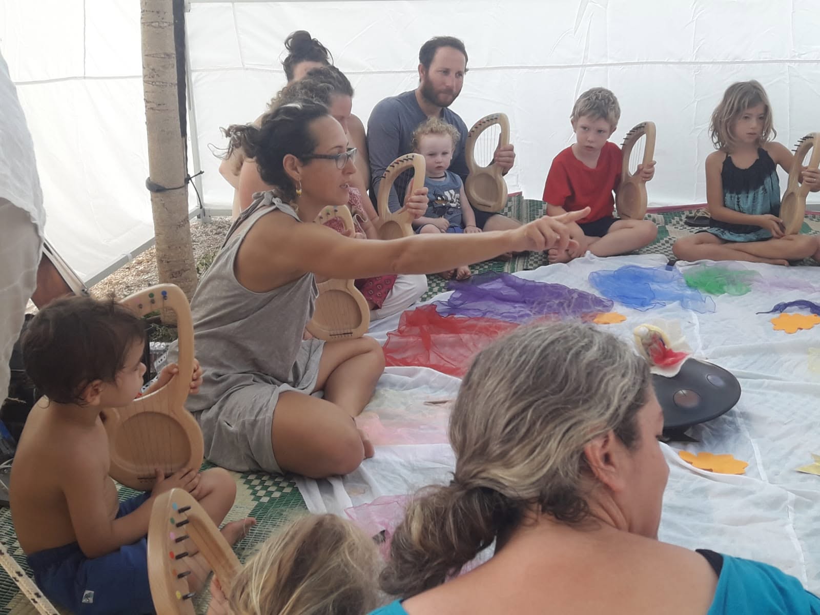 Children and adults make crafts together around a worktable in a tent.
