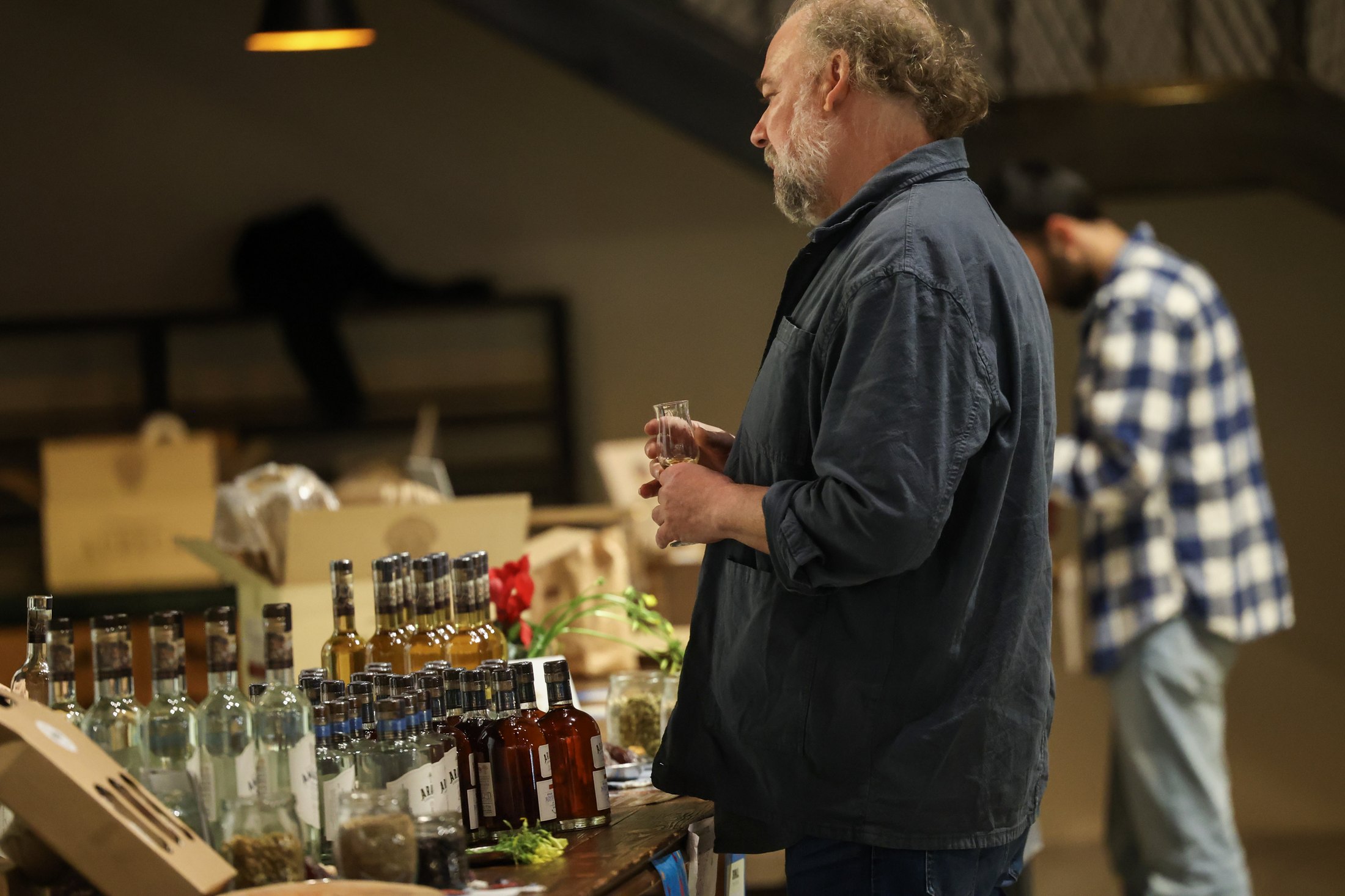 A visitor stands before a row of bottles at a stand.