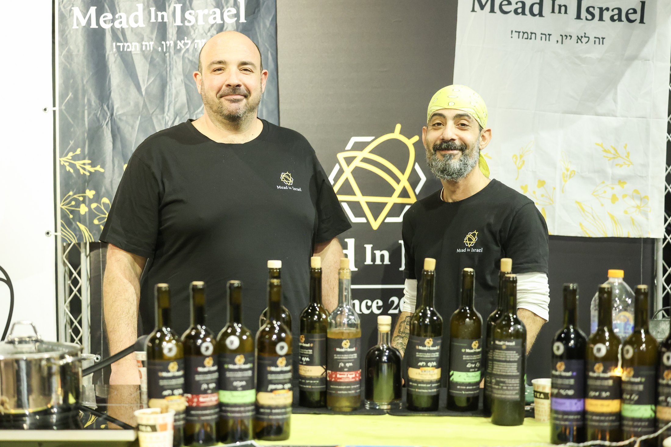 Two smiling exhibitors behind a Mead in Israel stand.