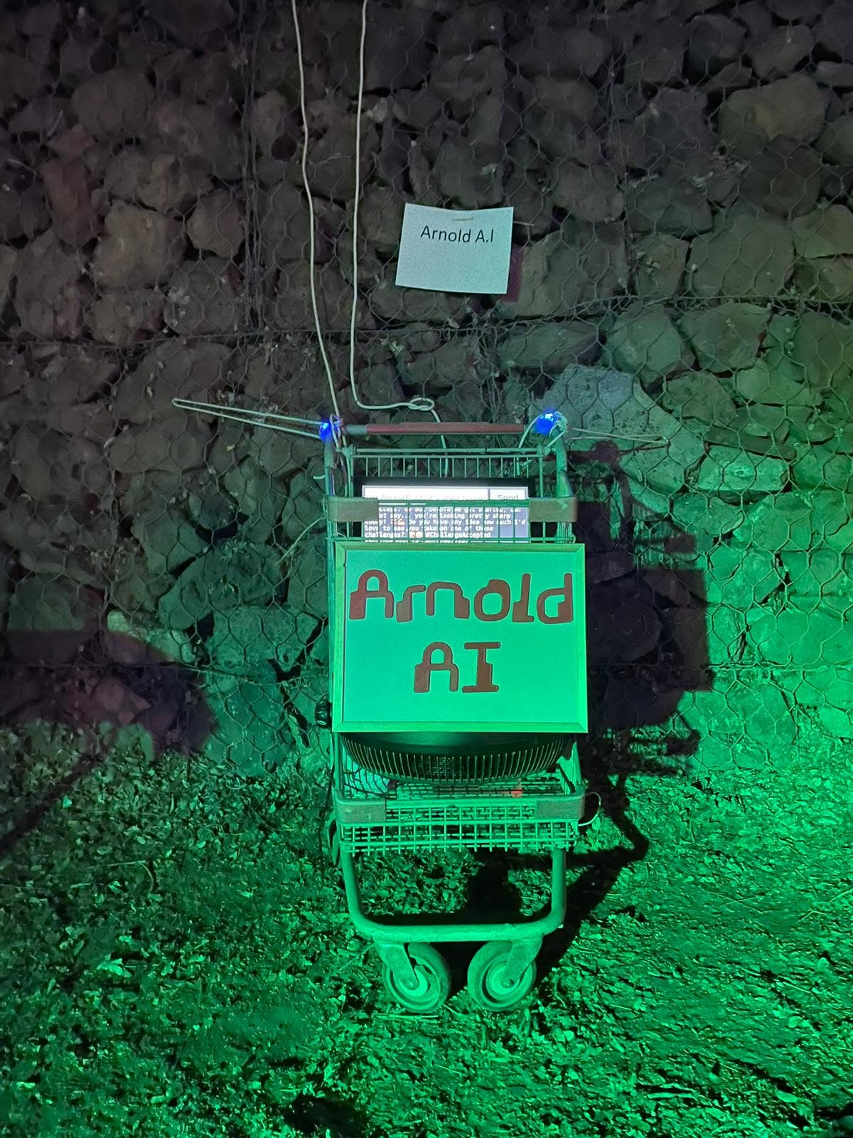 An Arnold AI sign hangs from a green-lit installation.