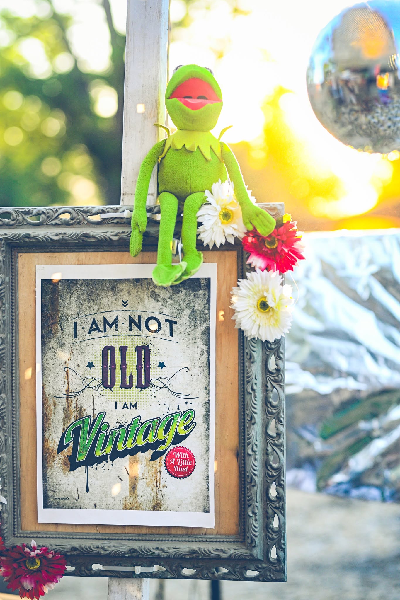 A green puppet and a Vintage sign on a tree trunk.