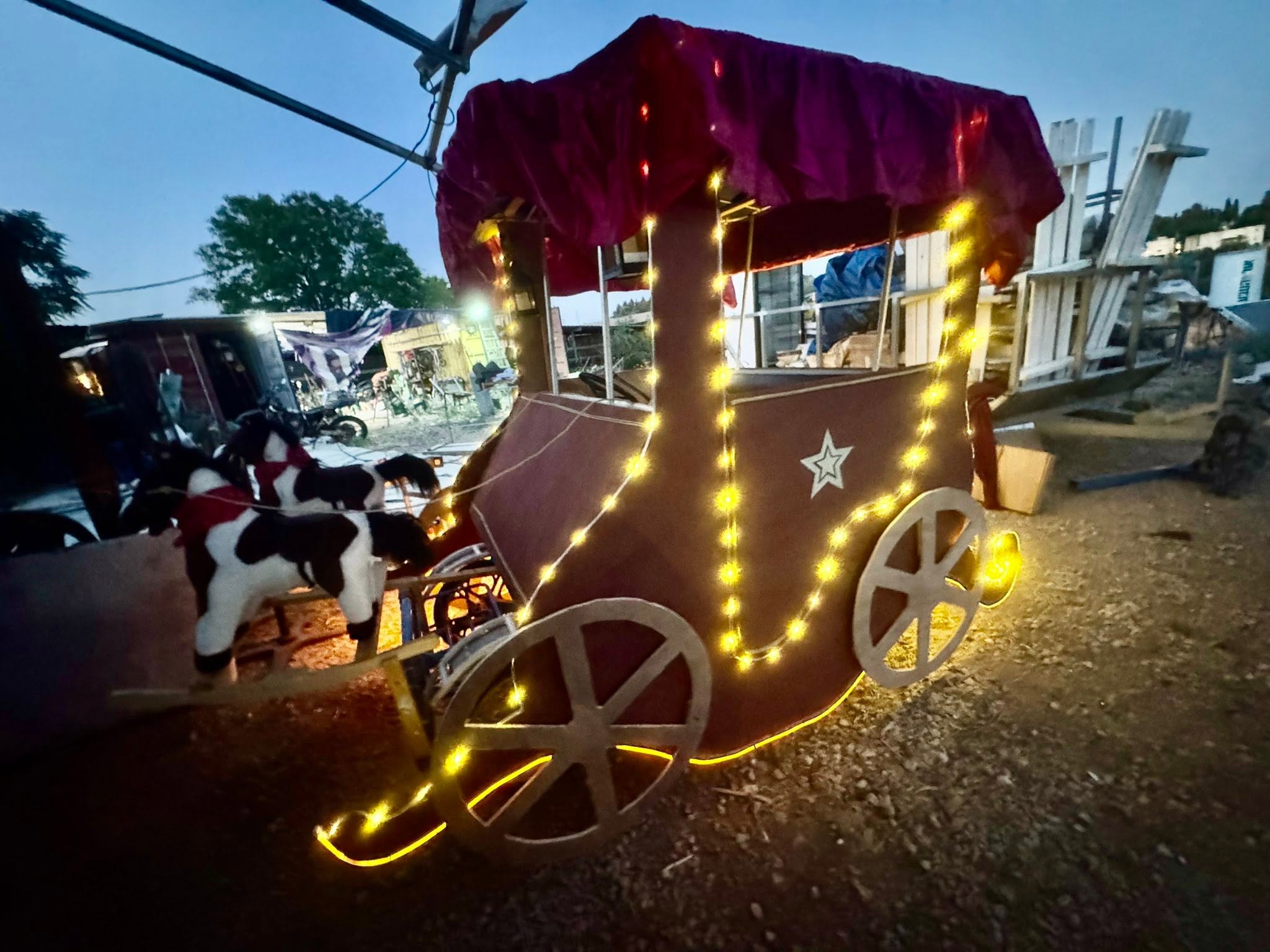 A small illuminated cart with a purple fabric canopy by day.