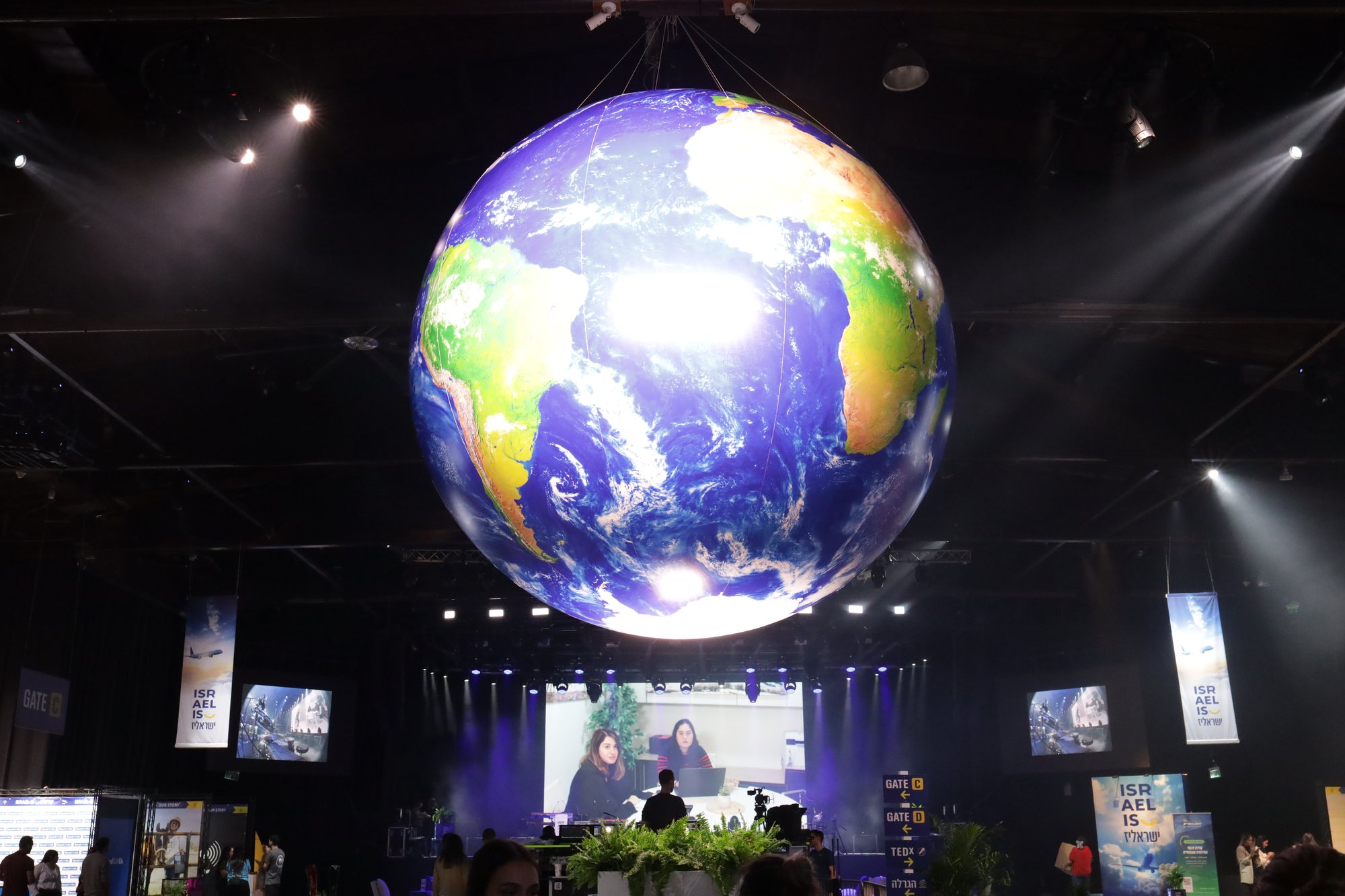 A glowing globe hangs above the audience in the hall.