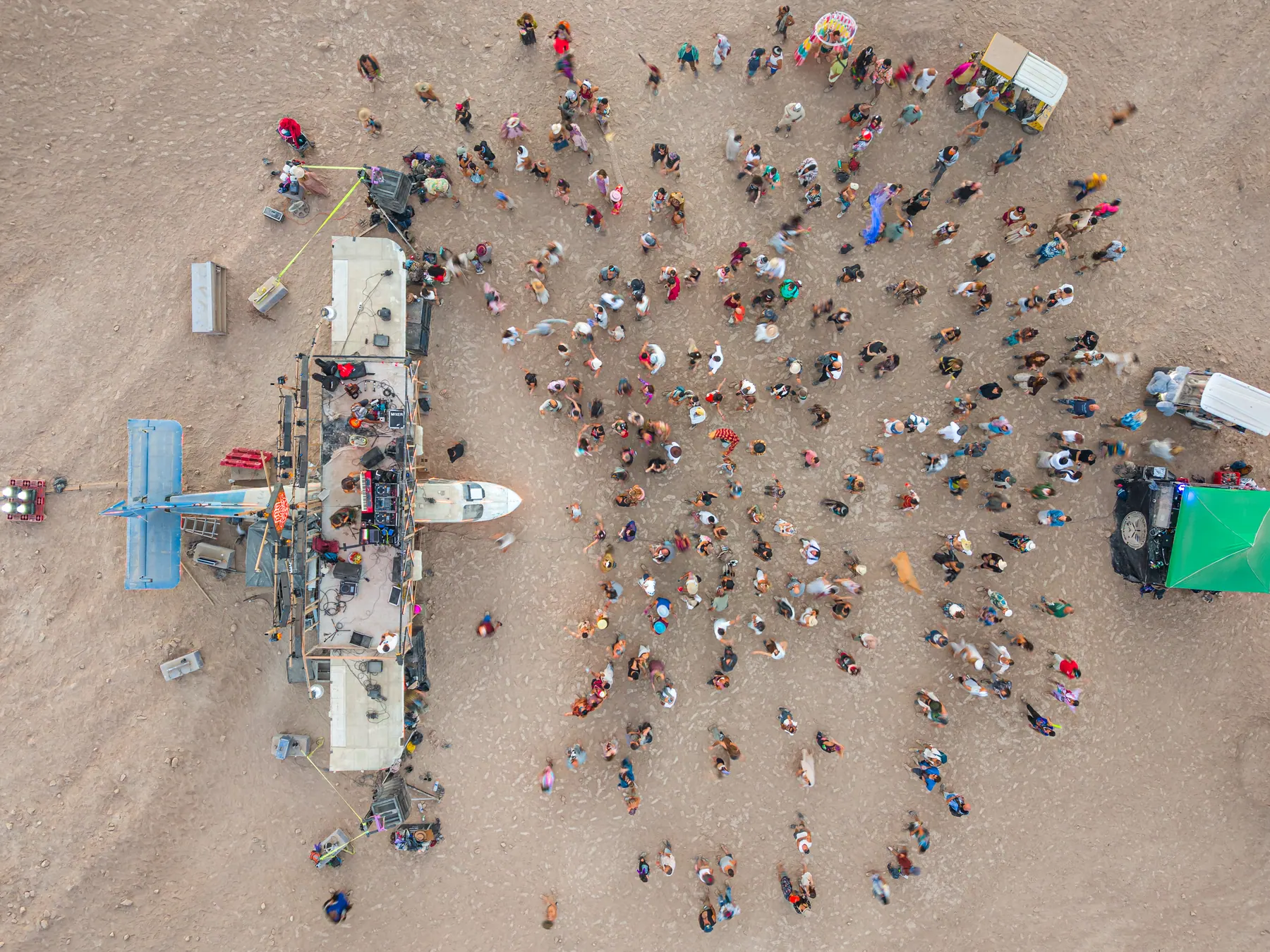 Overhead view of people gathered around a small art vehicle.