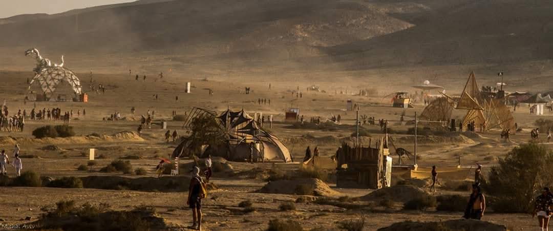 An open desert landscape dotted with art installations and people.
