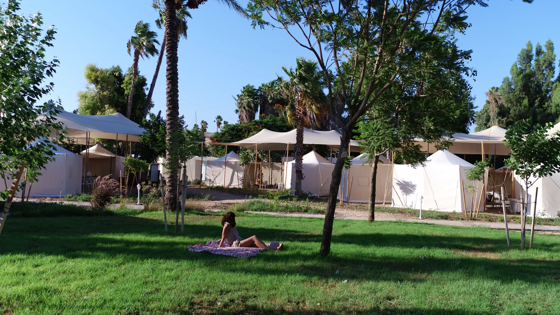White tent cabins around a shaded lawn.
