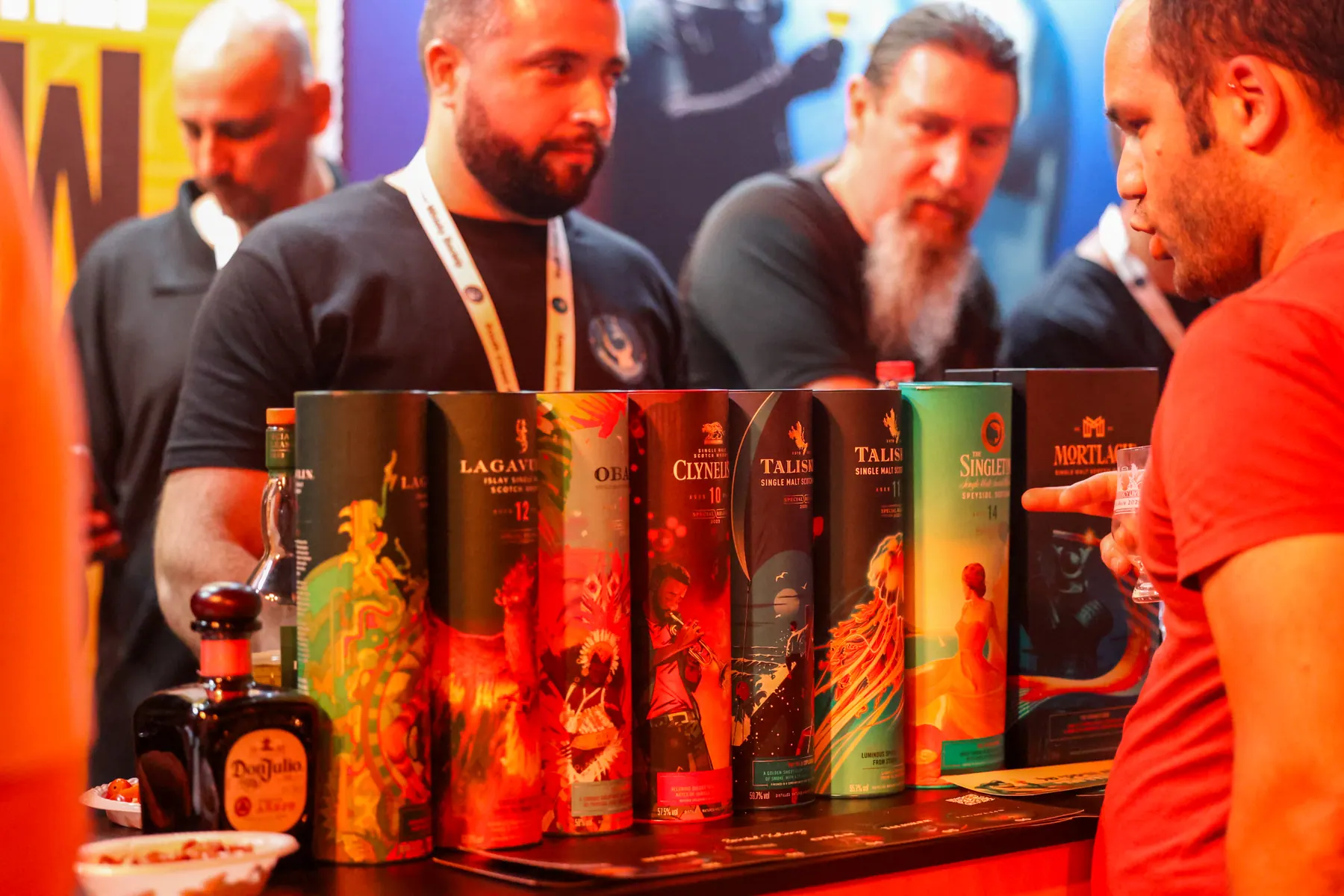 An exhibitor discusses a range of bottles with guests at a stand.