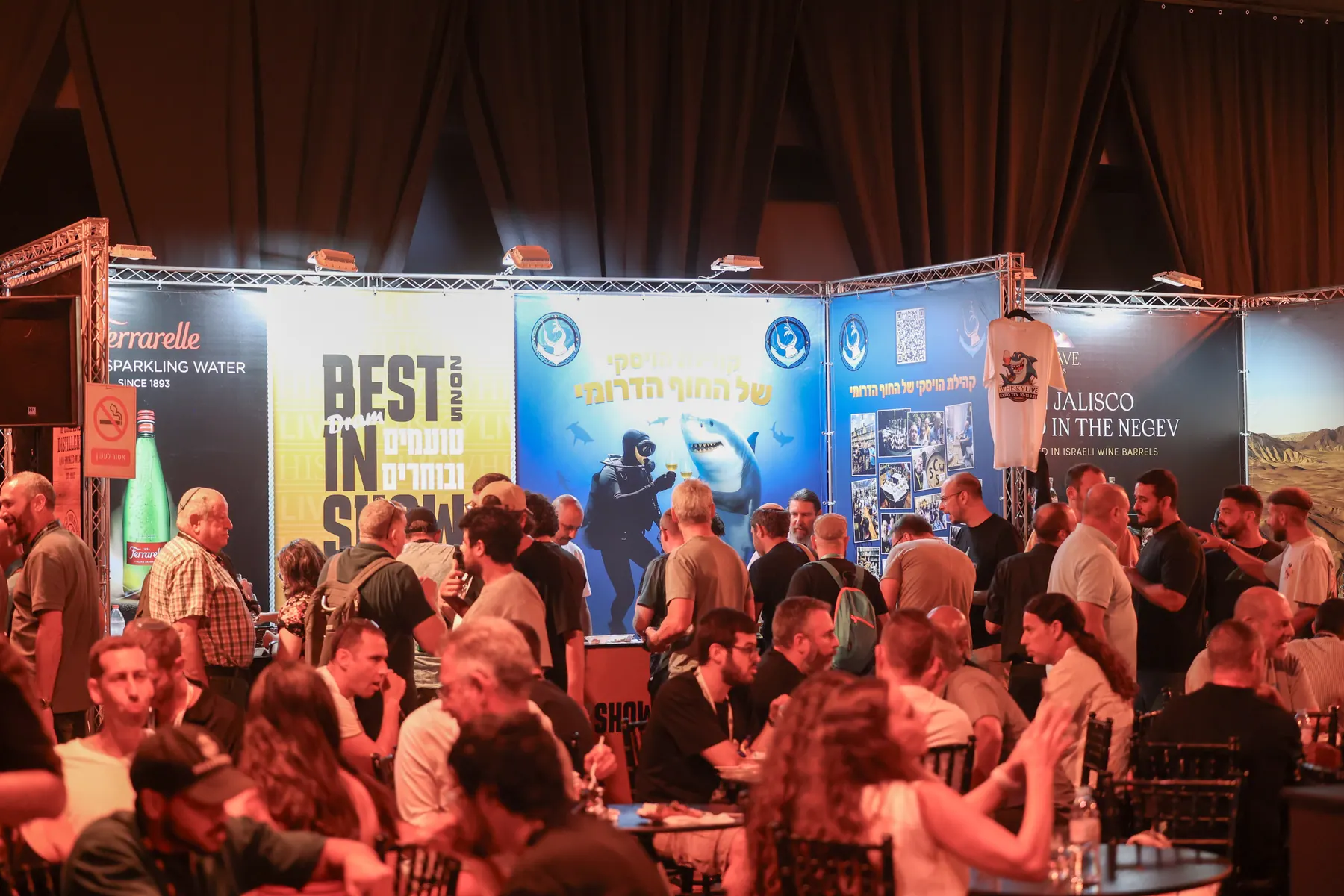 Visitors talk in front of blue-branded exhibition stands.
