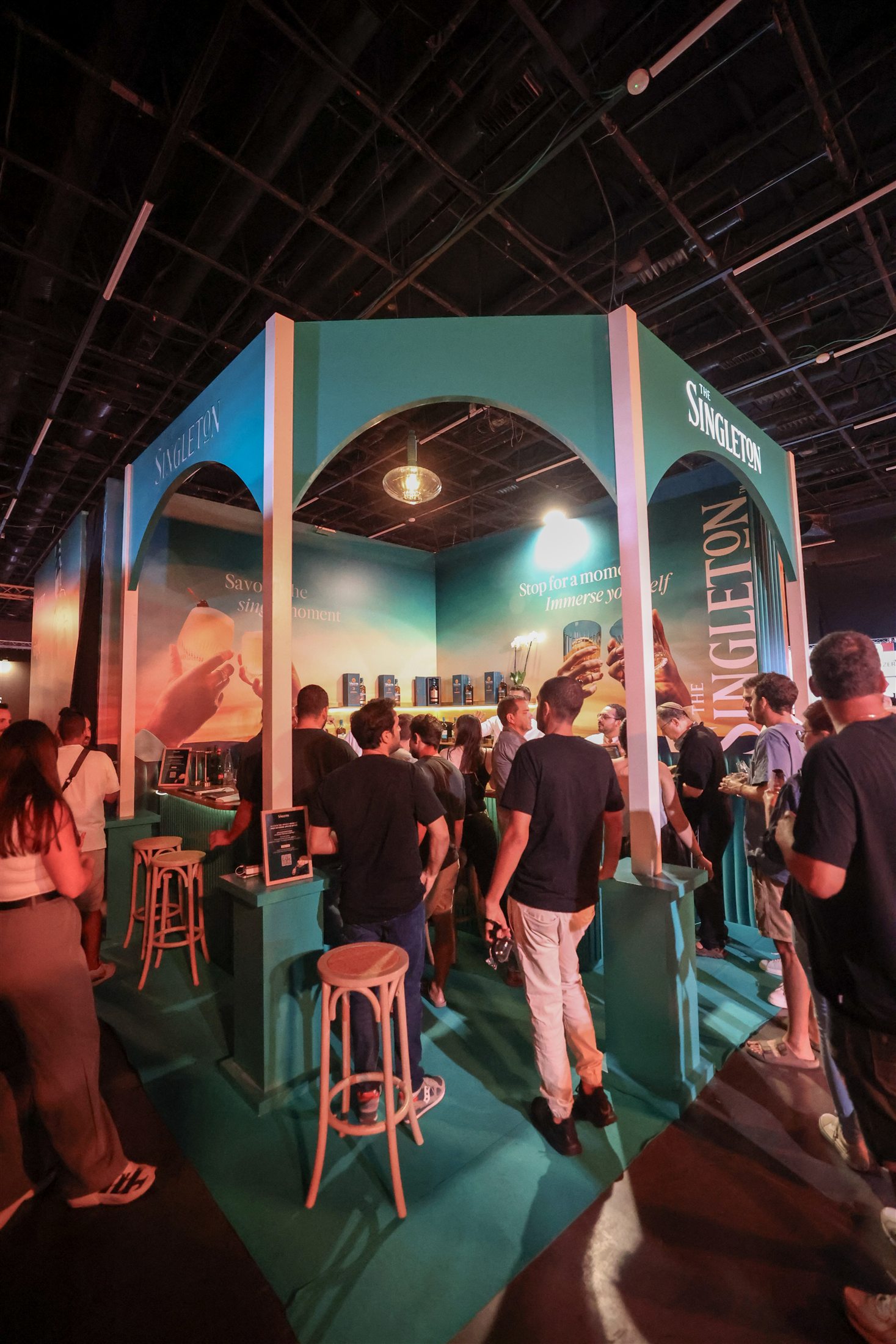 Visitors move between tasting stands beneath illuminated arches.